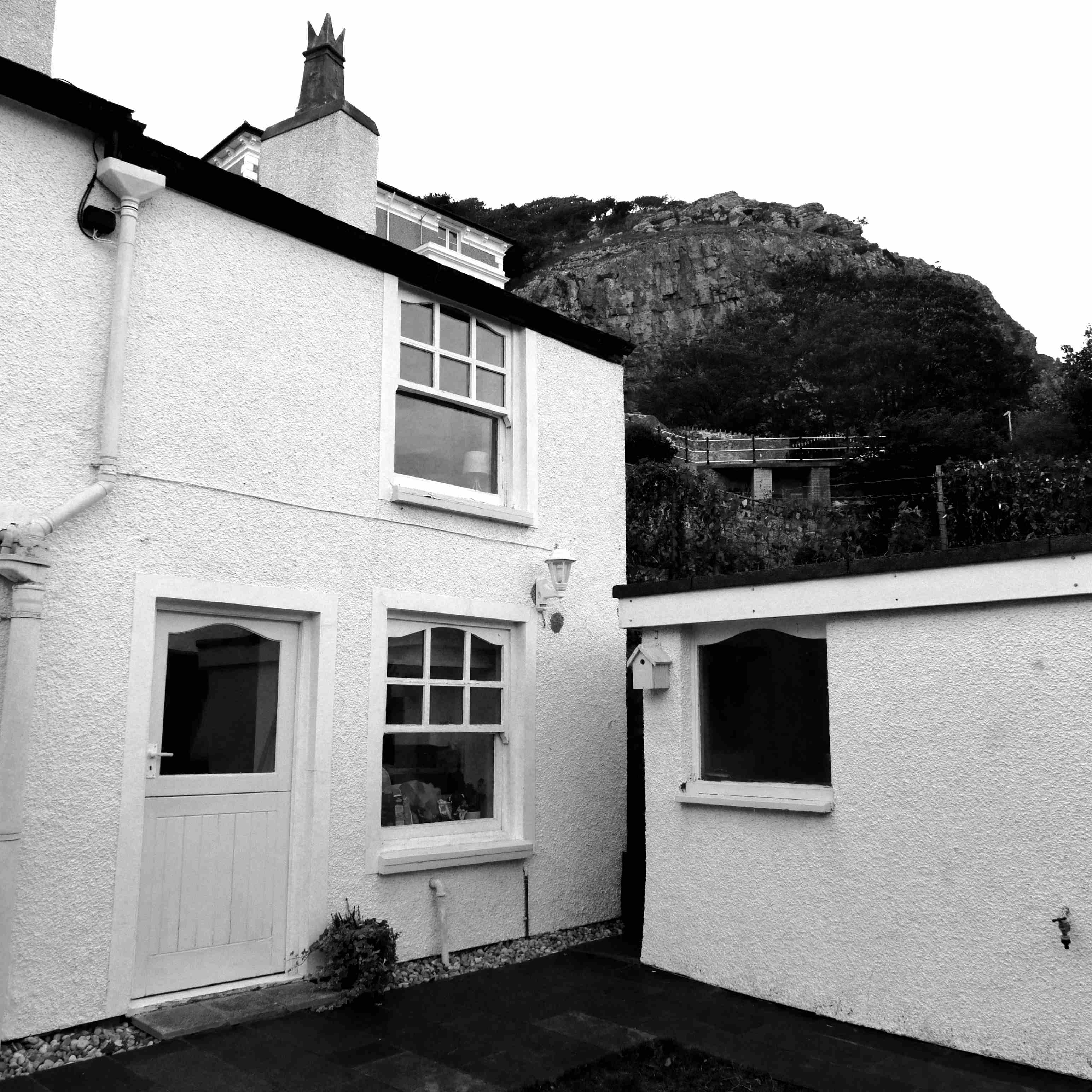 Photograph of a white cottage on a hillside