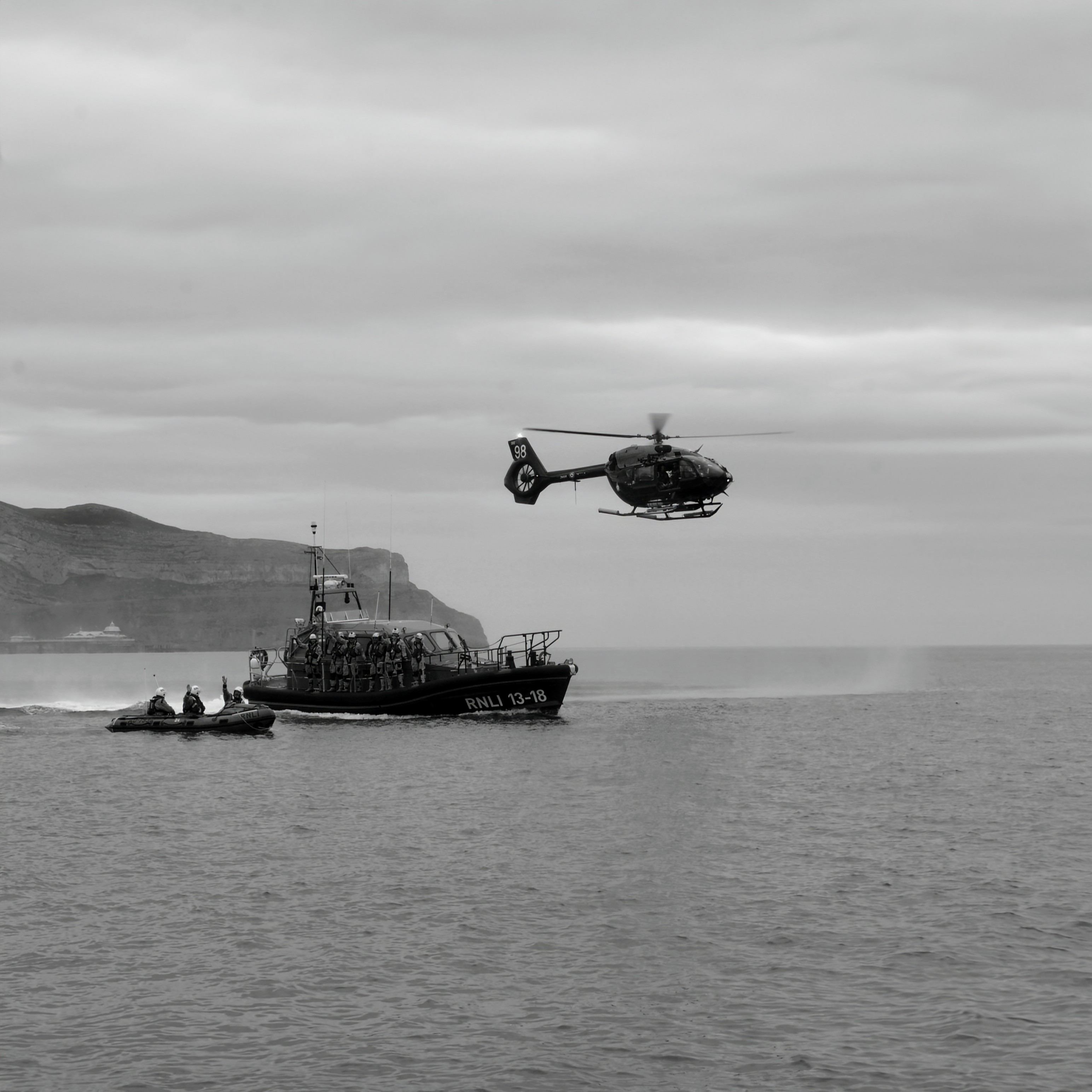 A small in-shore lifeboat, a large off-shore lifeboat, and a helicopter travelling side-by-side