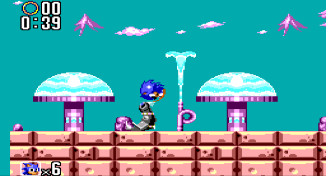 Screenshot of a Sonic curled into a ball, being bounced on the nose of a robotic seal. There are purple fountains with spurts of water visible in the background.